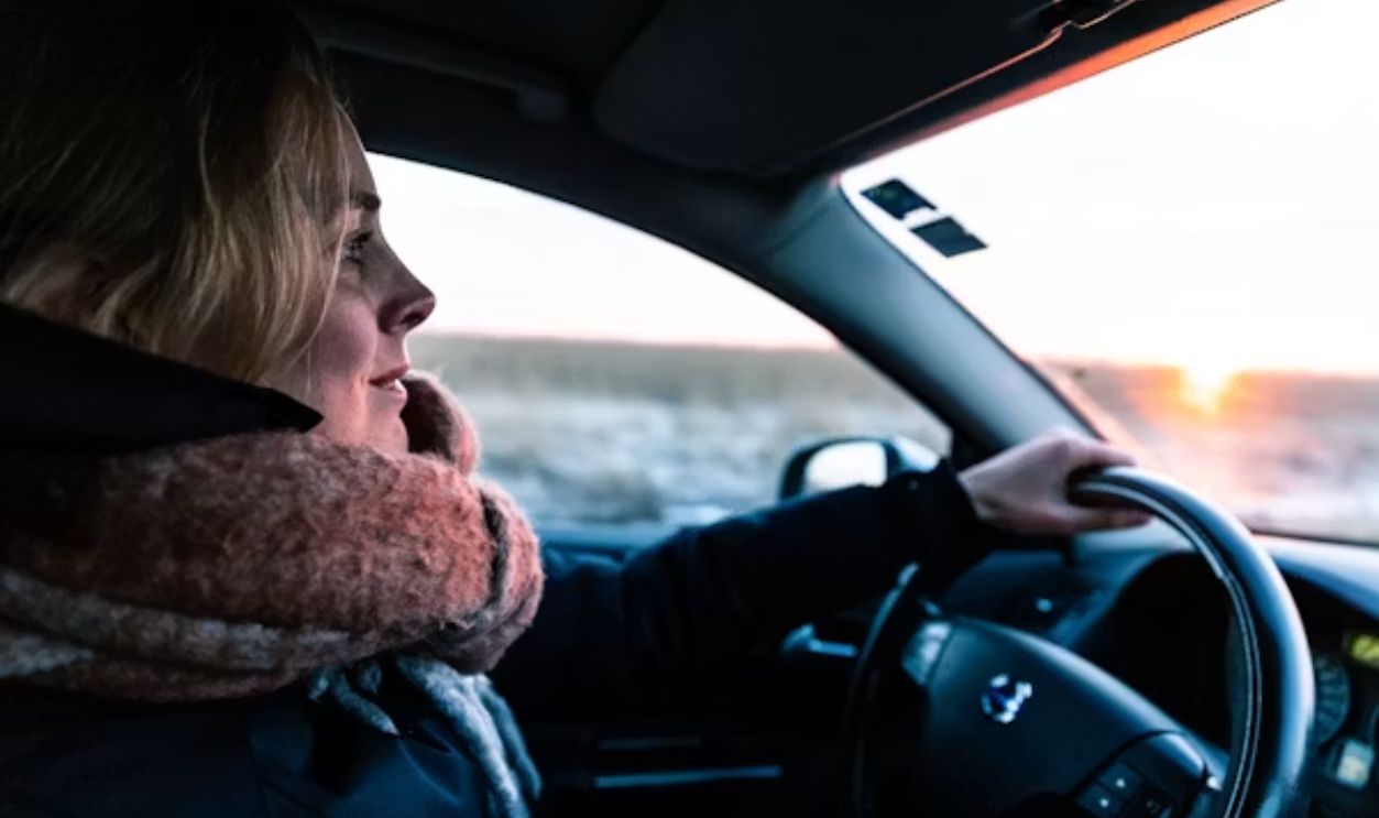 A car driving before sunrise on a snow-covered rural road