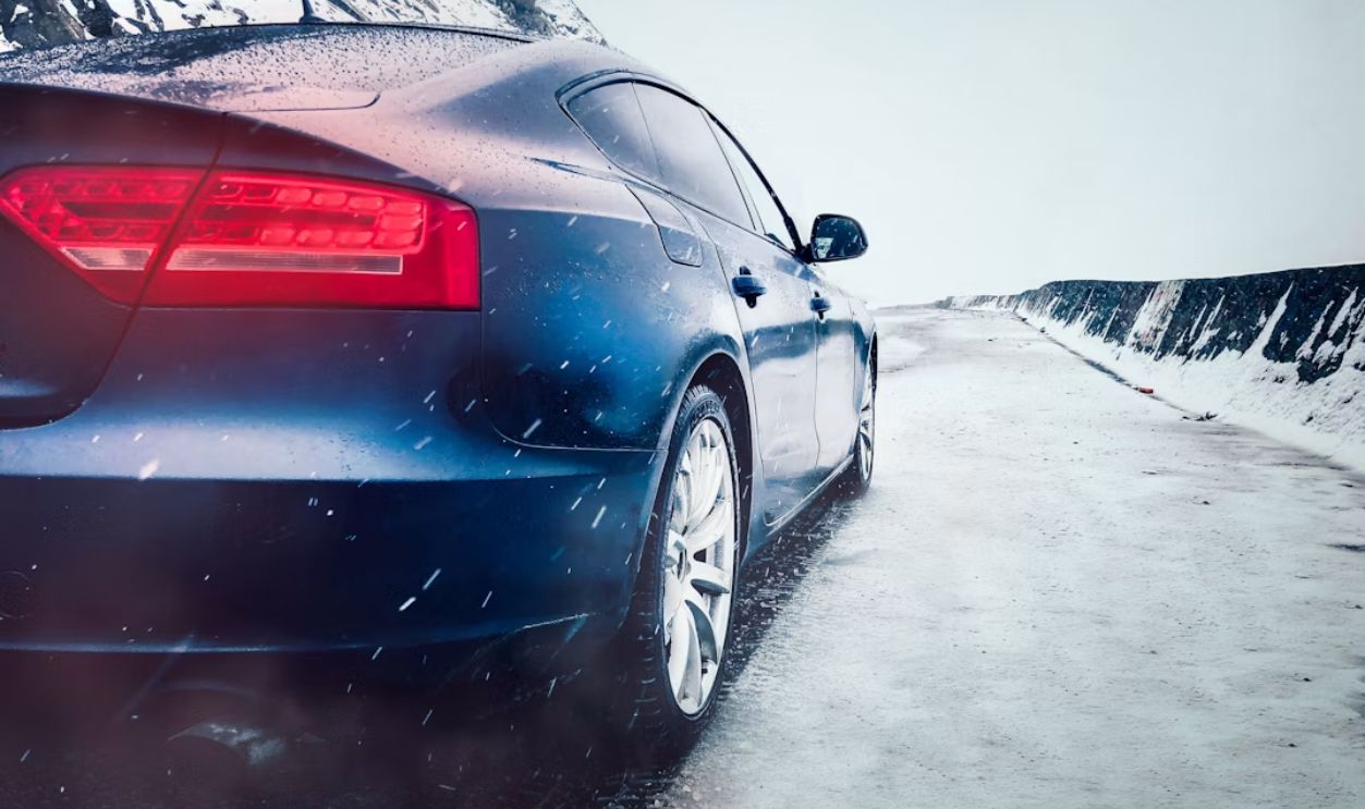 A car driving on a road with a light dusting of snow