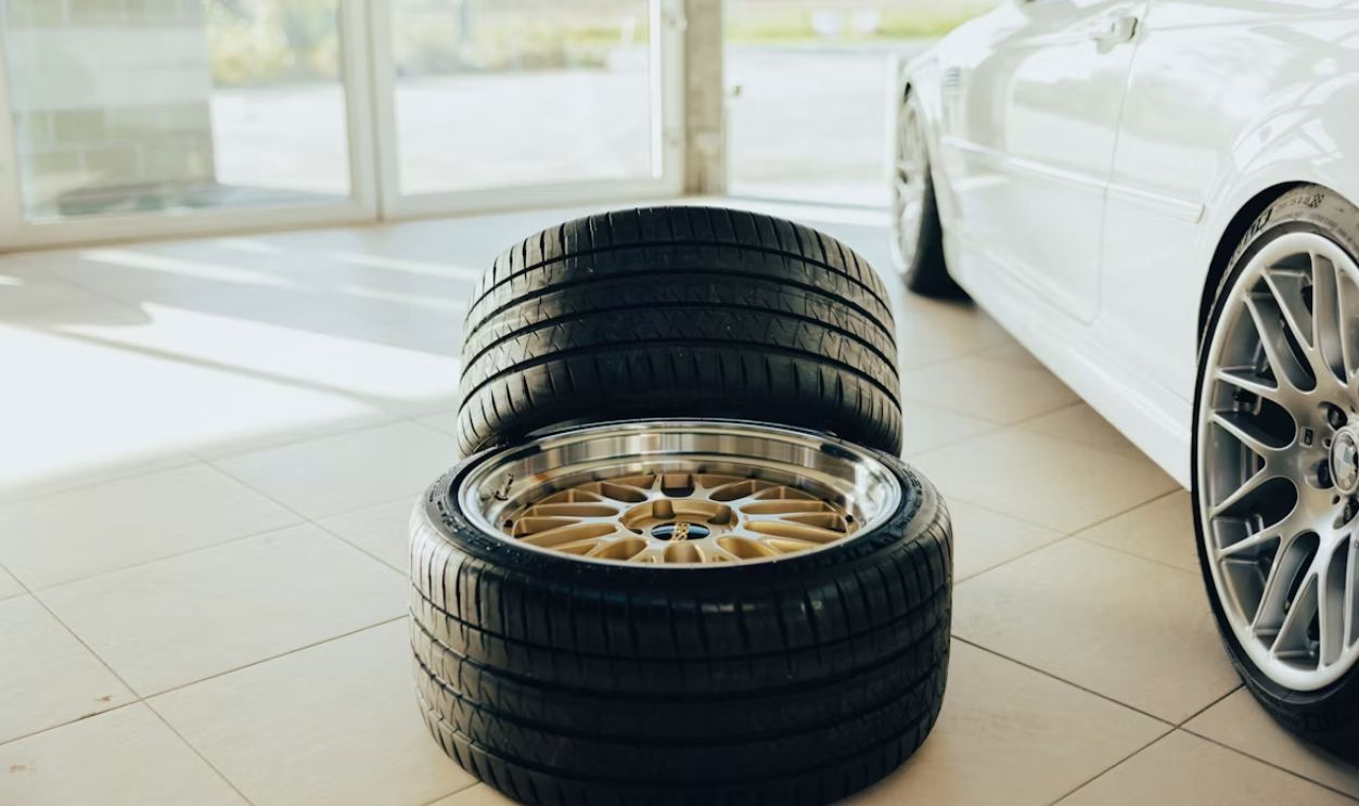 a white car parked in a garage next to two tires