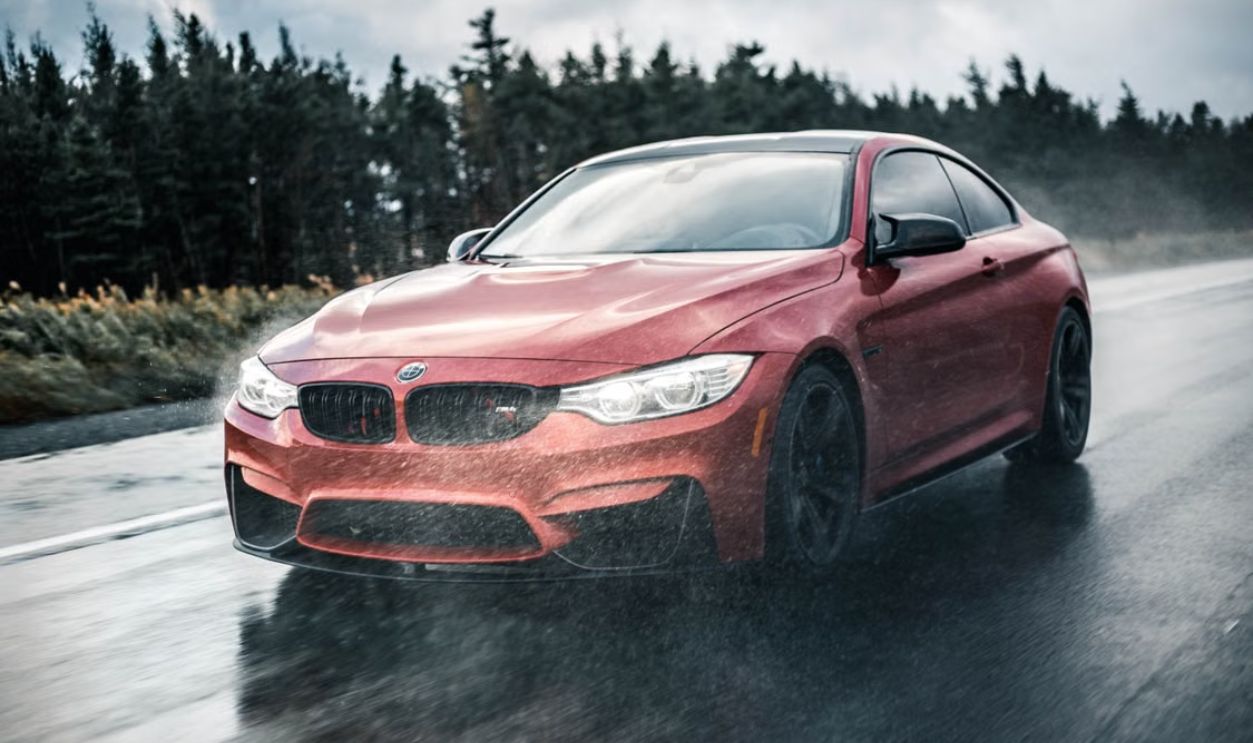 A sleek red sports car driving fast on a wet road with blurred motion and rain in the background.