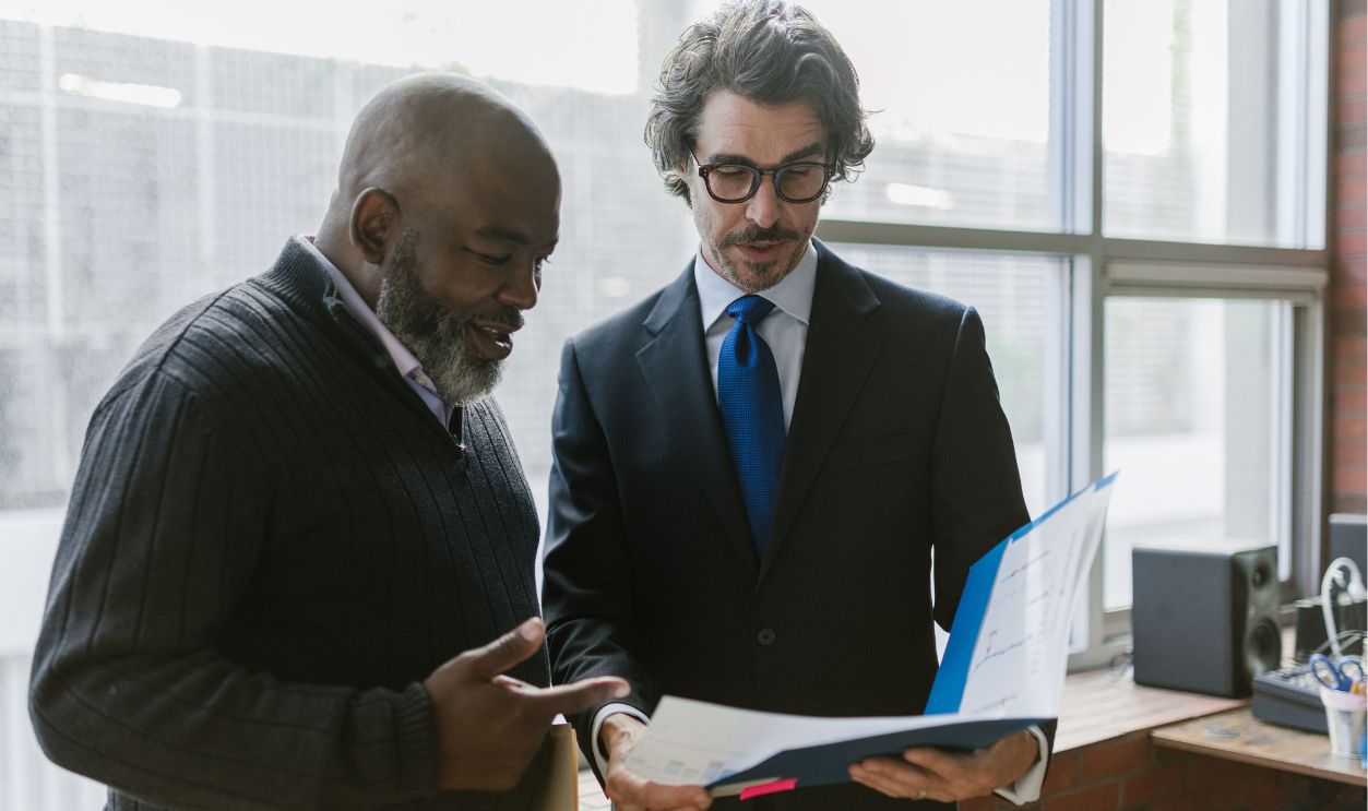 Two businessmen discussing and reviewing documents in a modern office