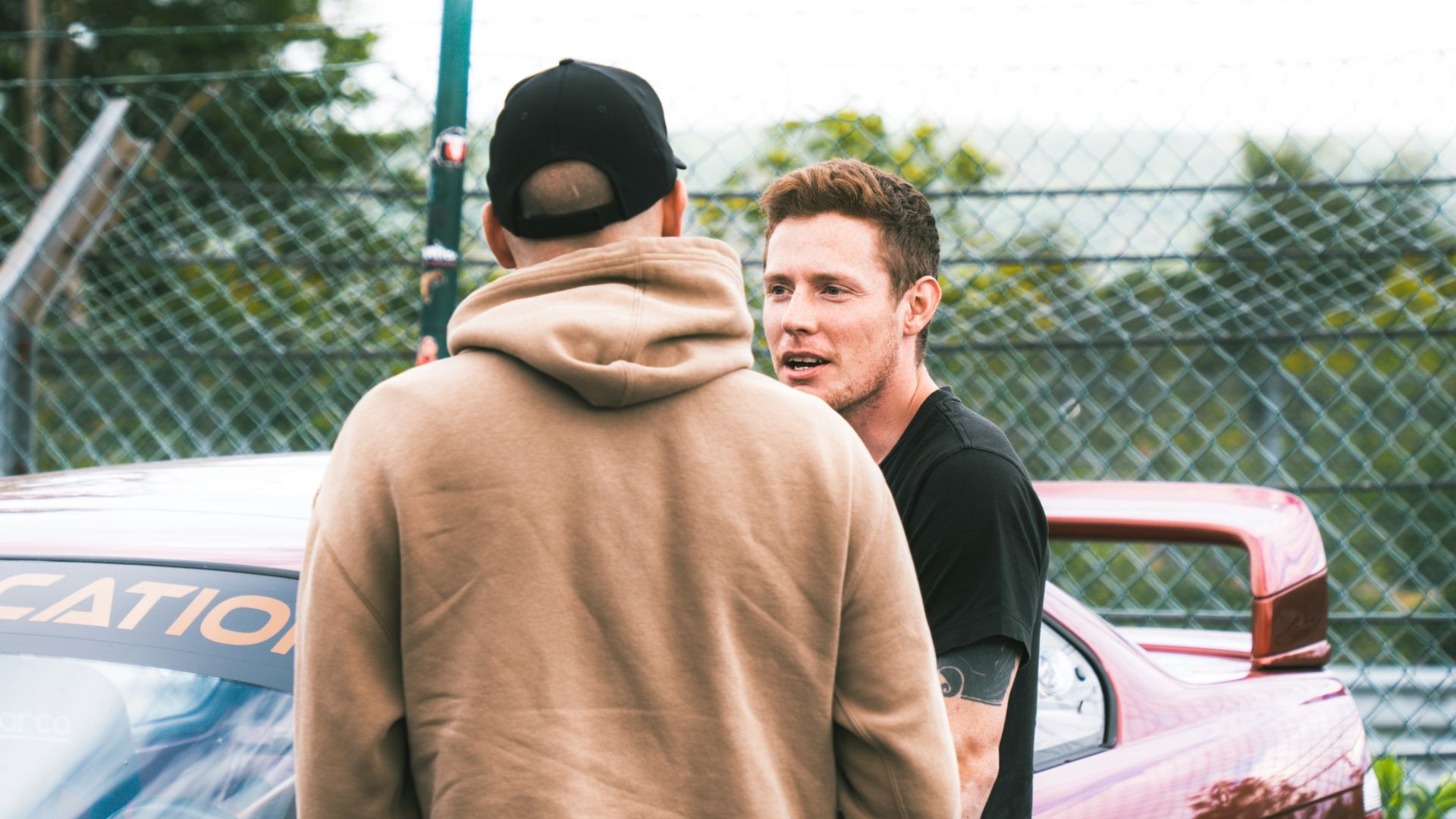 A group of men standing next to each other in front of a car