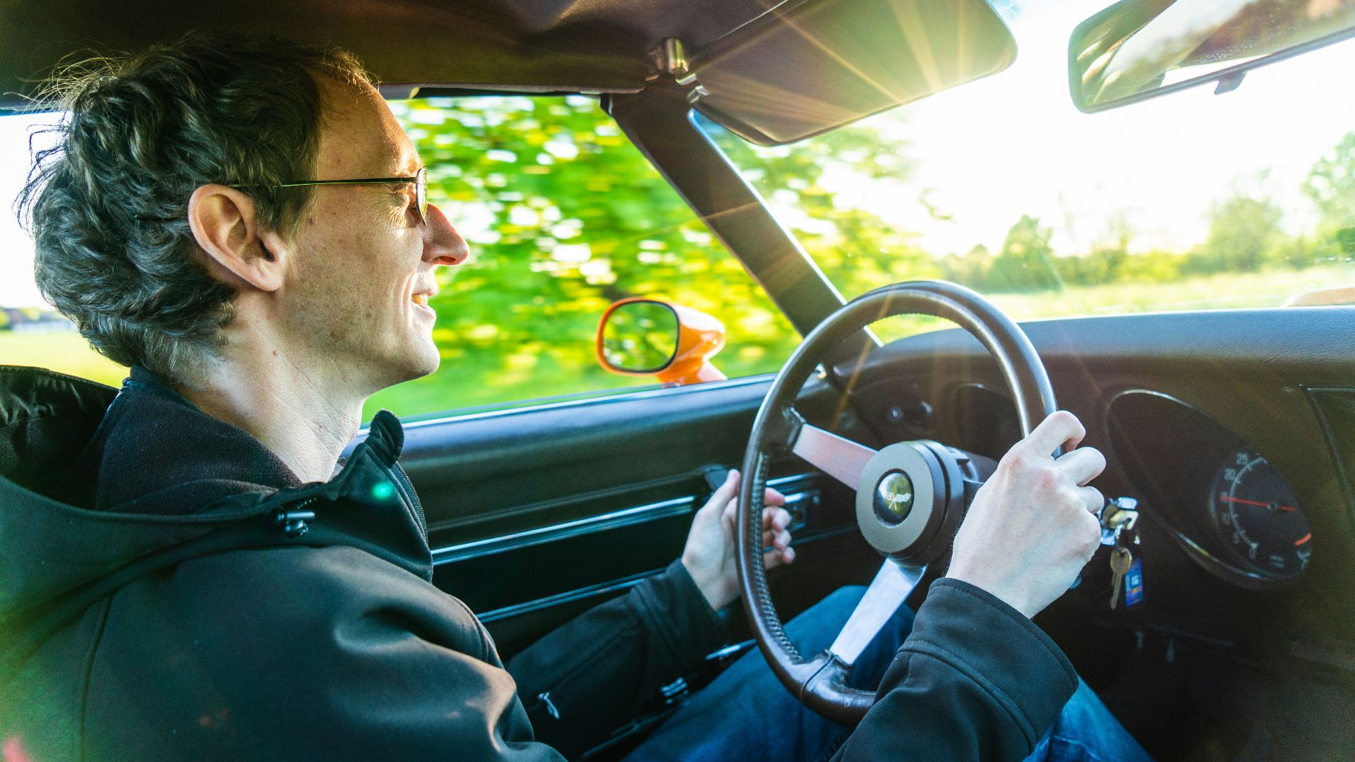 man in green jacket driving car during daytime