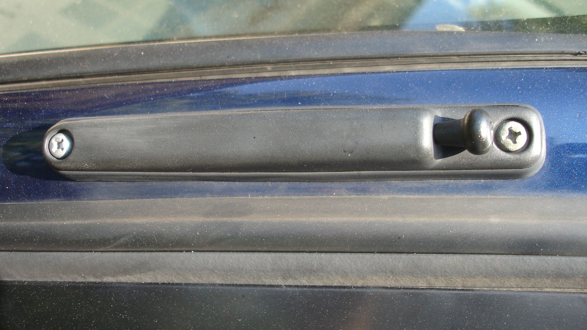 Car radio stock antenna, which has been compacted by sliding the whip down into the car frame. The antenna is attached to the car with two Phillips head screws, and it terminates behind the dashboard into the car radio with a Motorola plug.