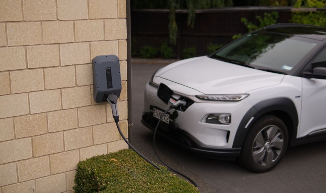A white electric car charging at a station in Christchurch, New Zealand, showcasing modern eco-friendly transportation