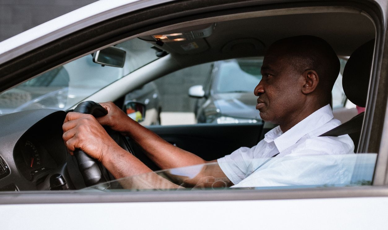 Side view of an adult man driving a car