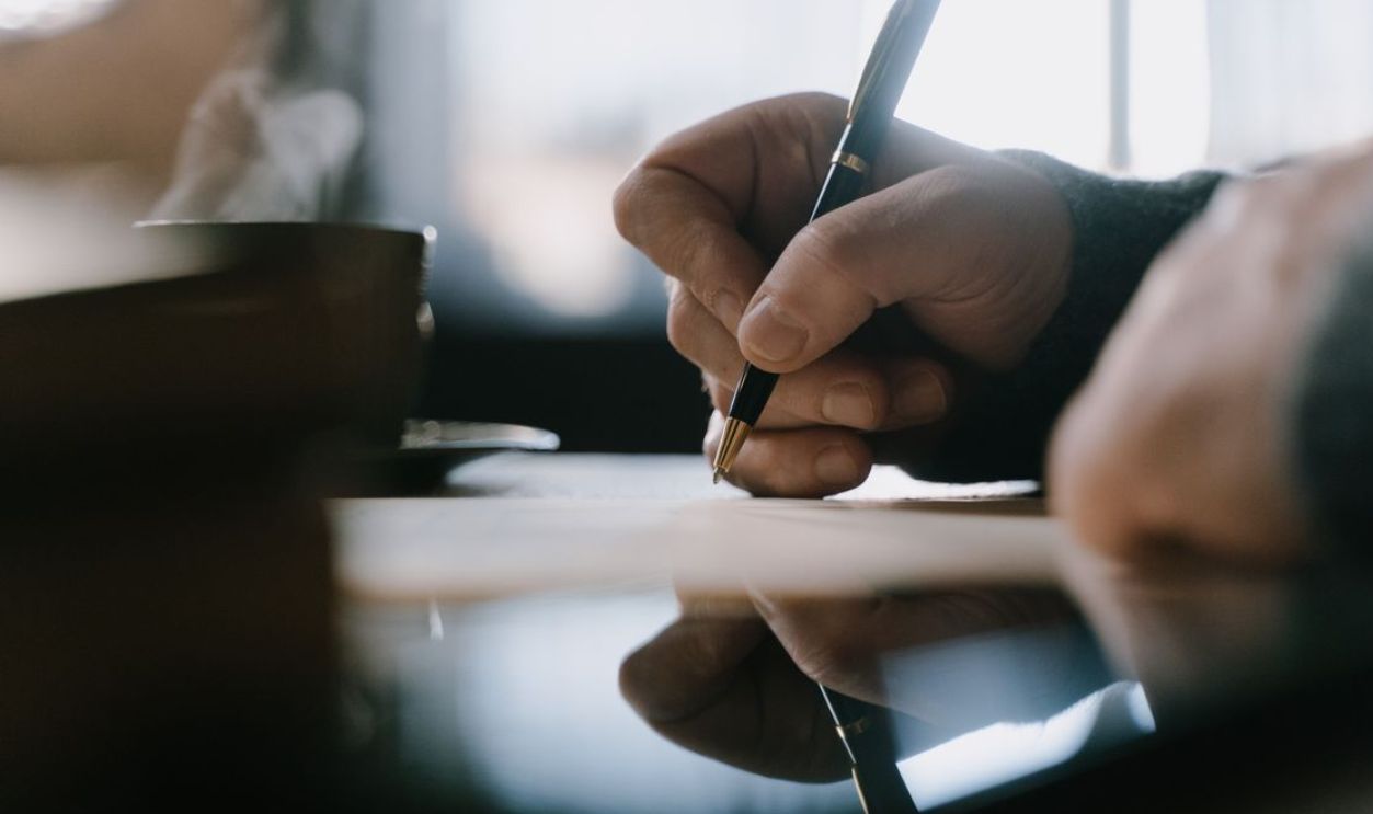 Focused adult hand writing with pen in a notebook, capturing creativity and concentration indoors