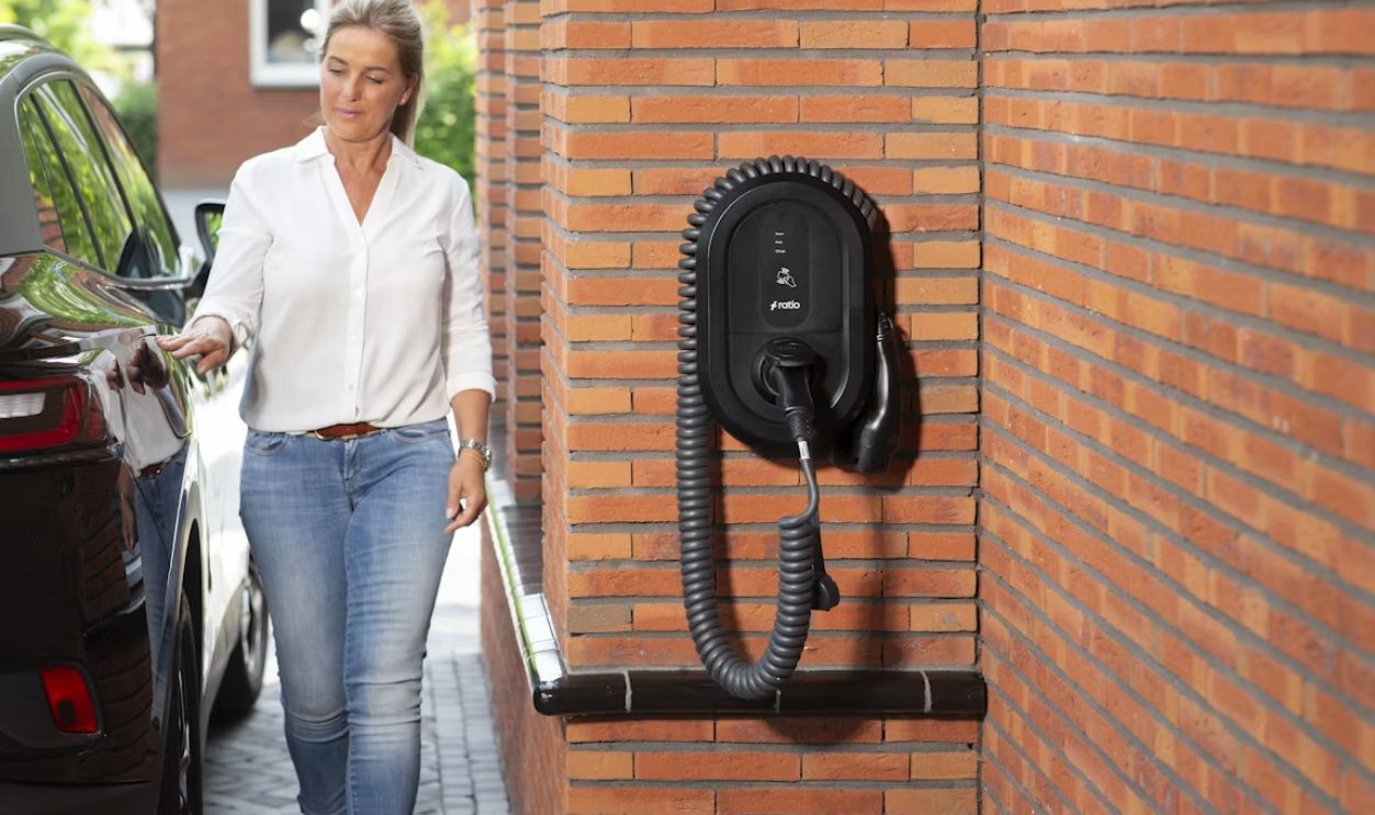 Woman plugging electric car into wall charger