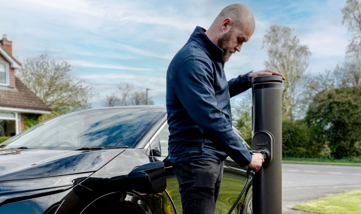 Man charging an electric car at an outdoor station