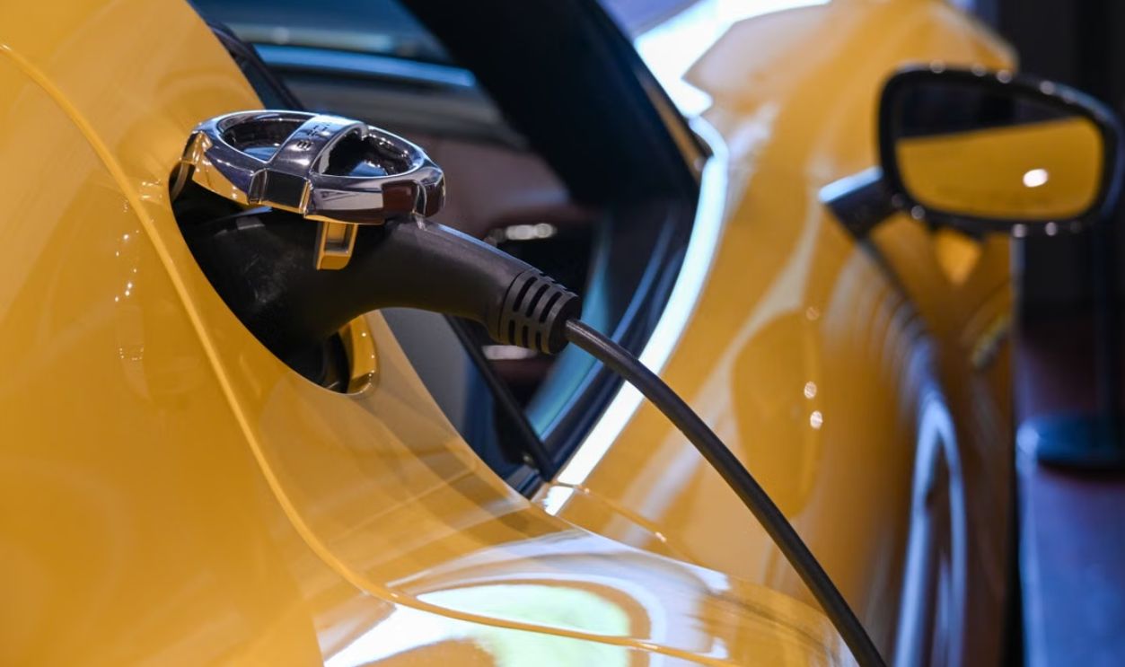 Close-up of a yellow electric vehicle charging with a plugged-in cable indoors