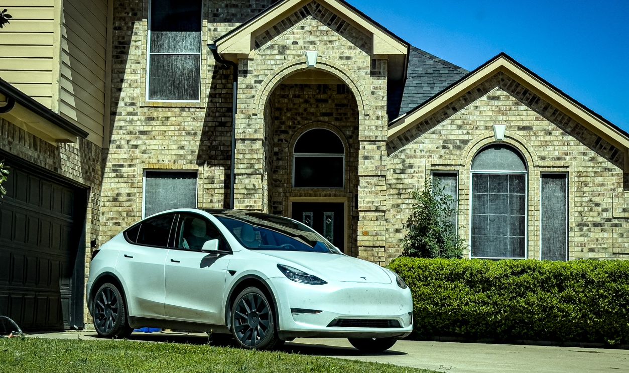 Stylish white electric car parked by a classic brick house in sunny Mansfield, Texas