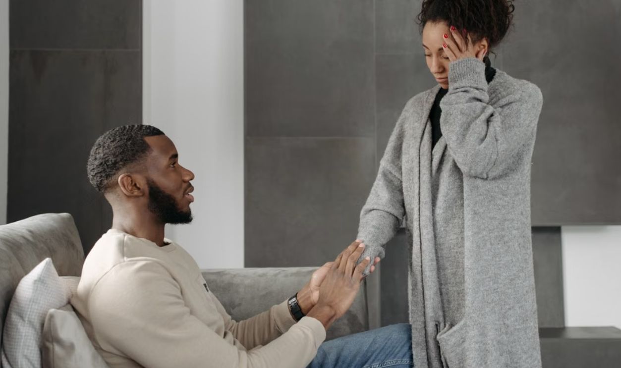 Man comforting woman with headache while sitting on a sofa indoors. Warm and supportive interaction
