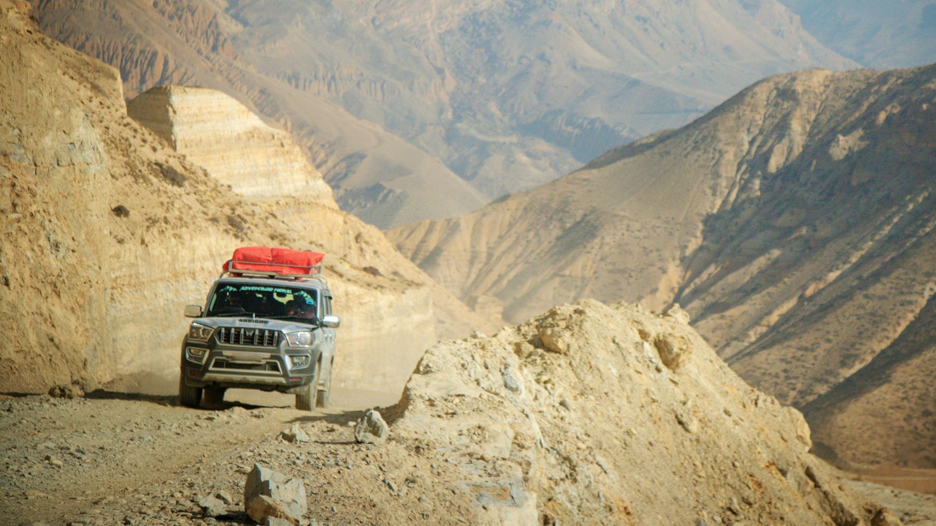 A jeep drives on a mountain road with scenic views.