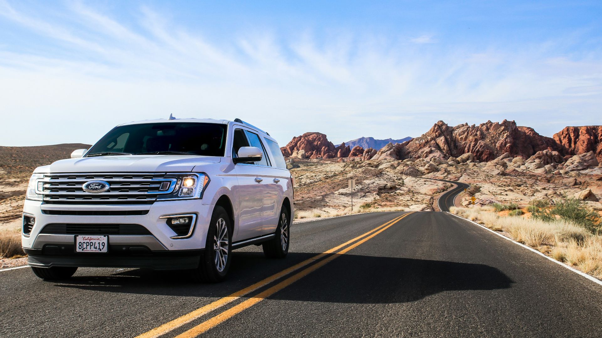 a white suv driving down a desert road