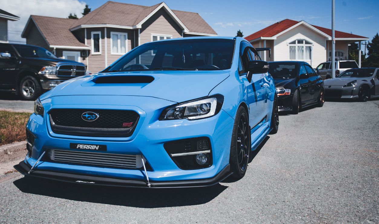 Bright blue Subaru parked on a suburban street with houses in the background