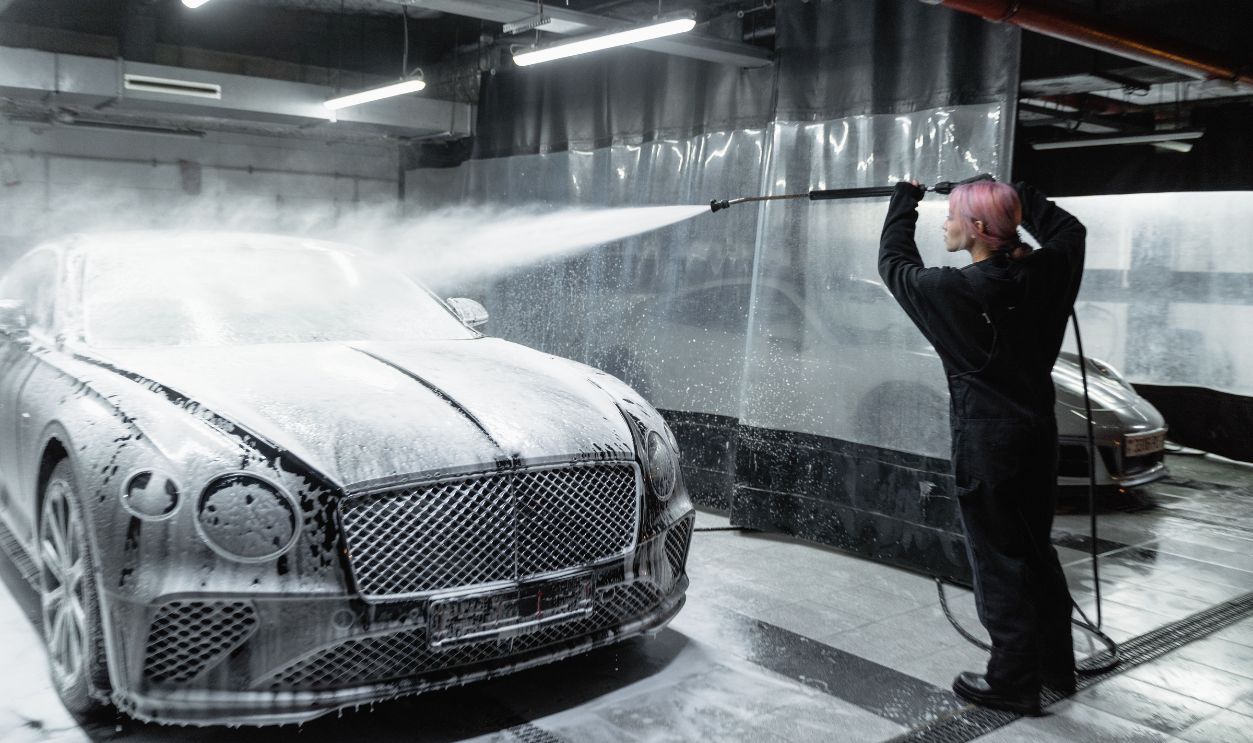 A woman expertly cleans a car using snow foam