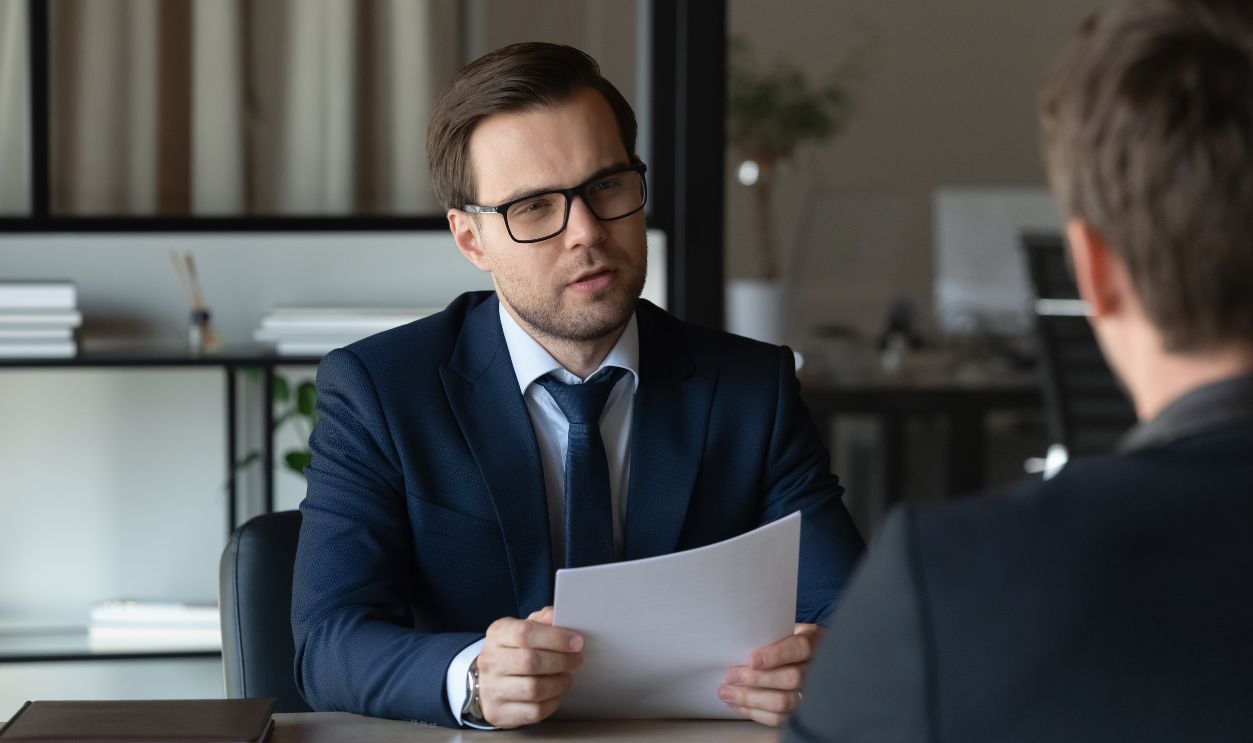 Serious concentrated employer with paper resume interviewing job candidate for hiring. Professional, lawyer, expert, advisor holding document, giving consultation to client. Business meeting concept