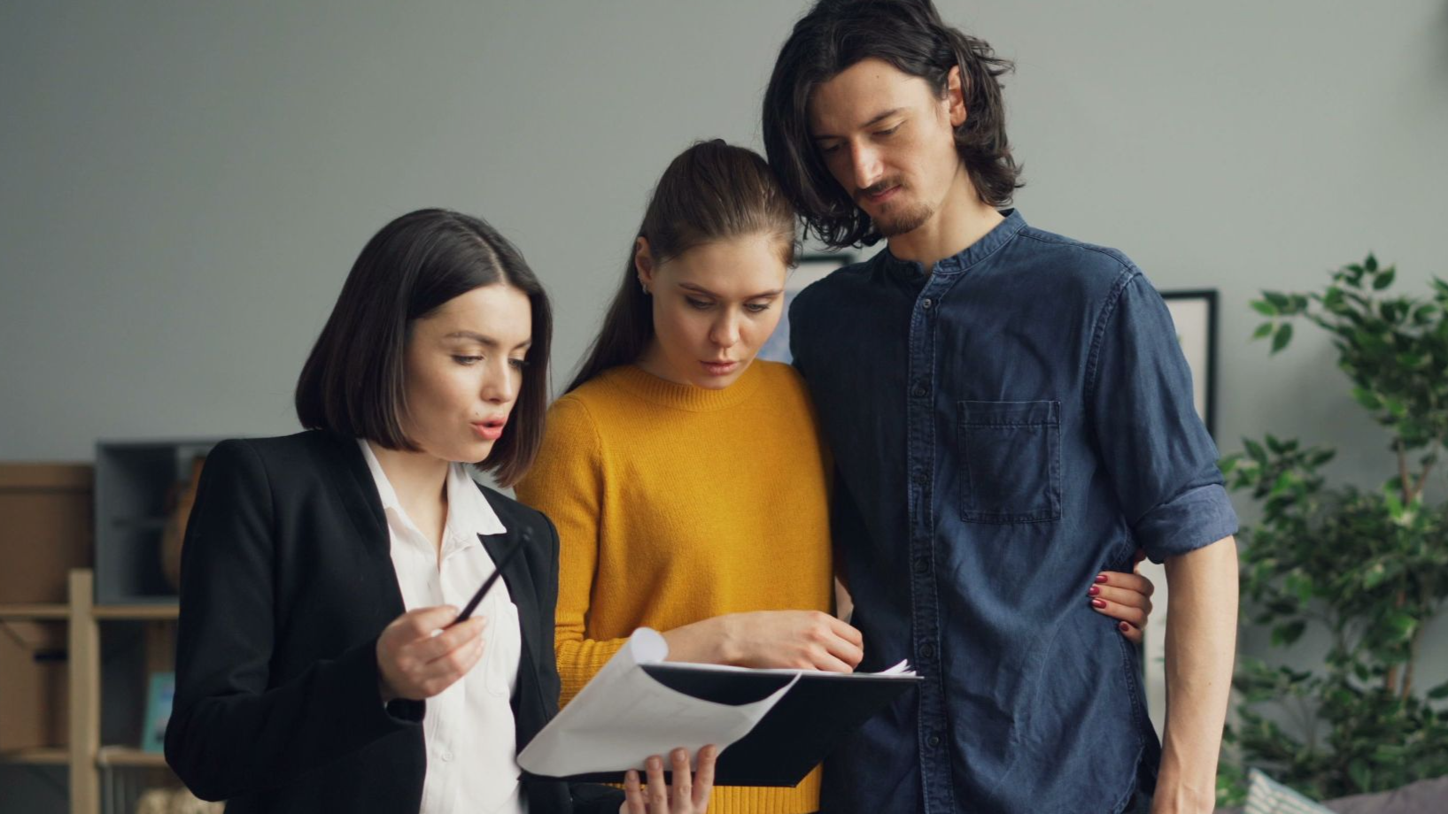 A couple reviewing documents with a real estate agent indoors