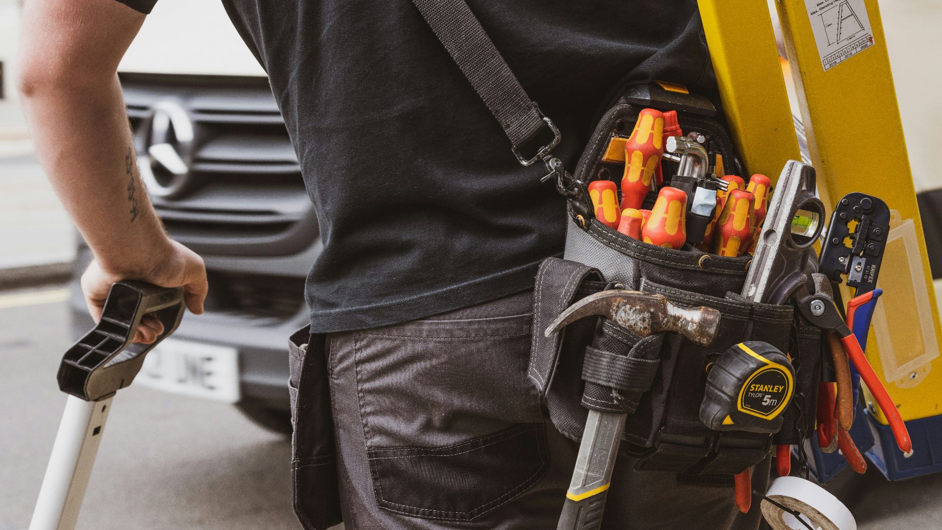 man in black crew neck shirt holding black and yellow power tool