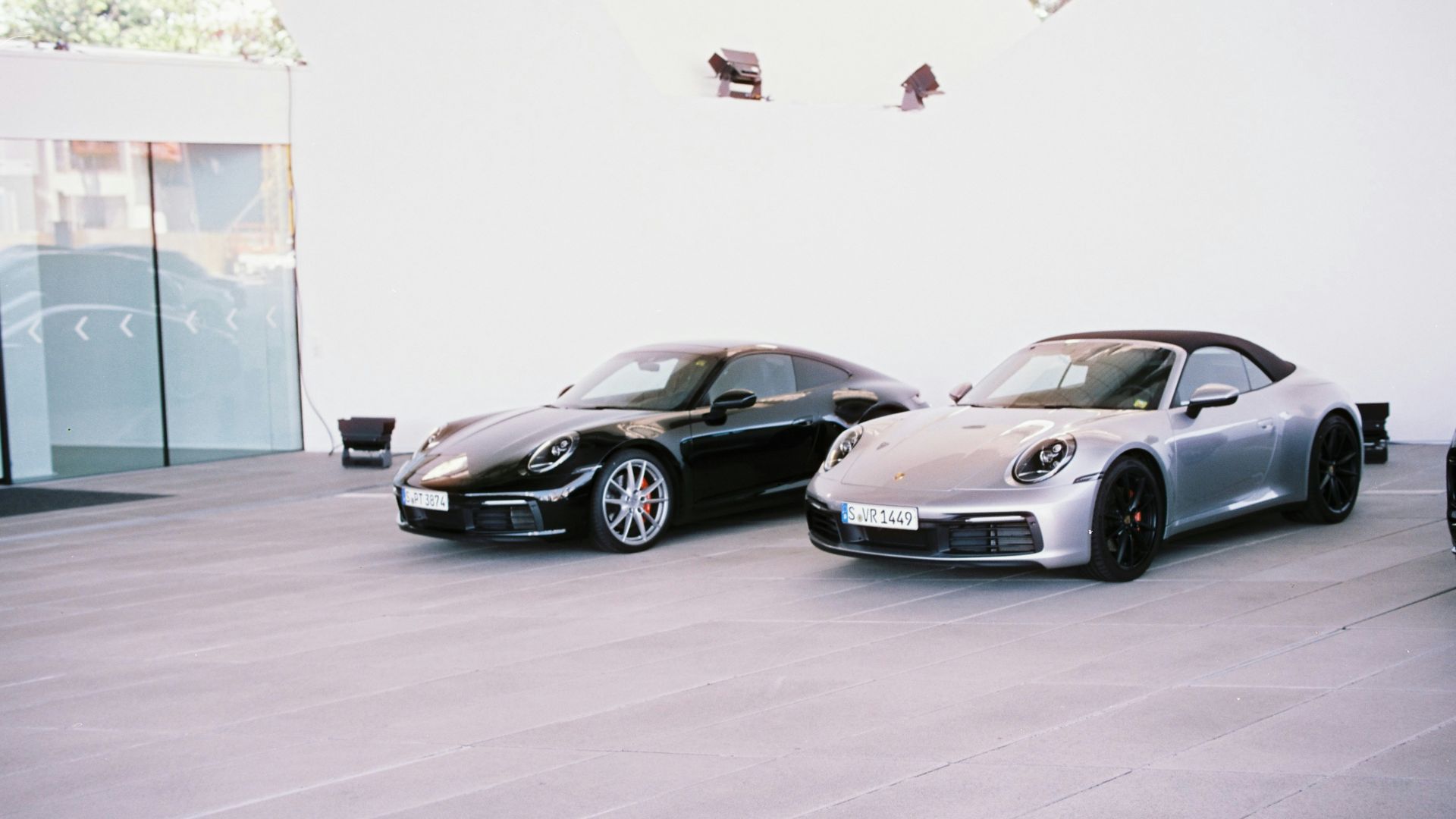 Two luxury sports cars parked outside a modern building
