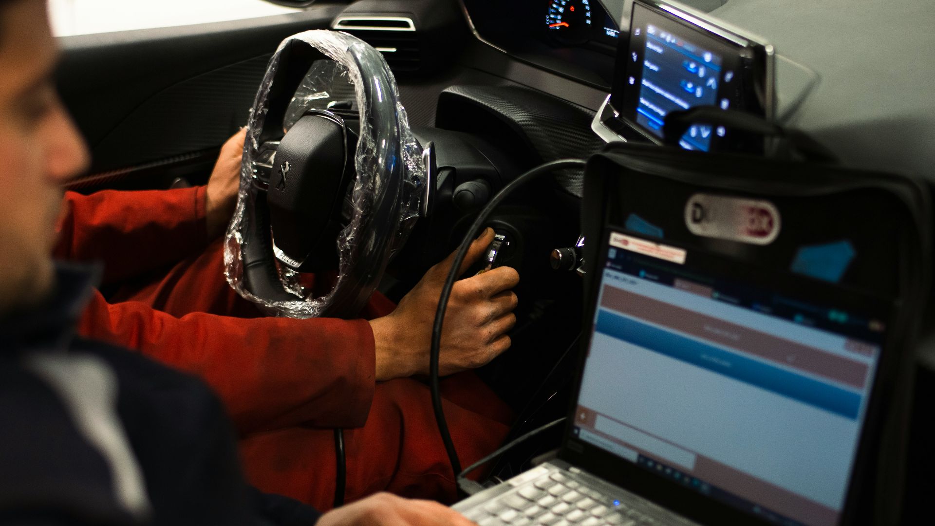 A man sitting in a car using a laptop computer