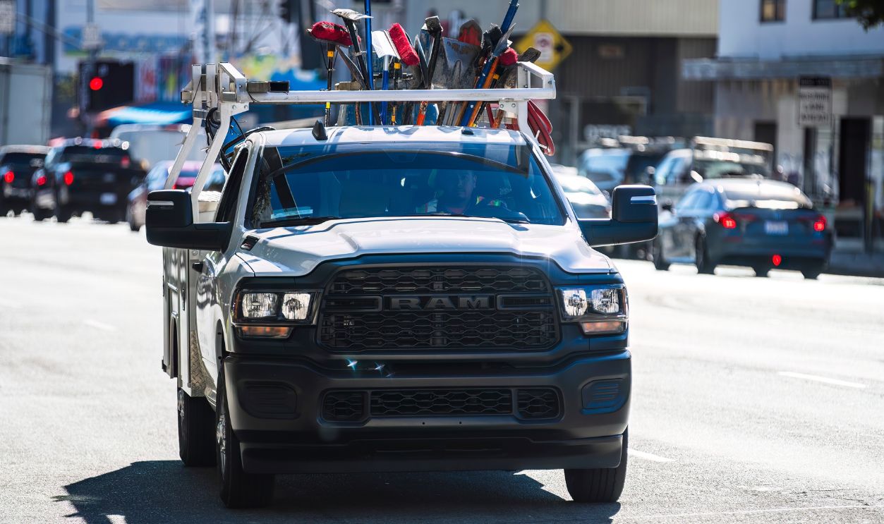 2024-11-15 Los Angeles USA RAM utility truck is driving on a city street, loaded with various tools and equipment securely fastened on its roof rack. 