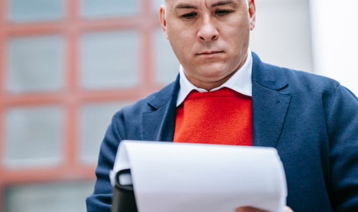 Professional man in smart attire reviewing paperwork outside modern building