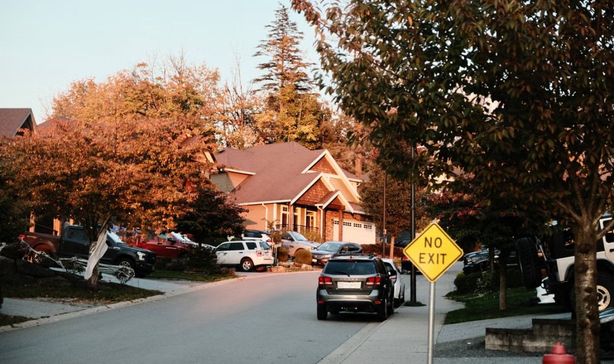 Charming suburban street scene with houses, cars, and a no exit sign in fall.
