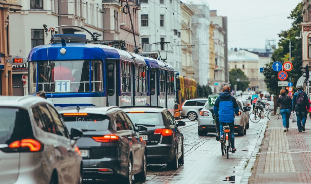 Bustling street in Riga, Latvia showing cars, tram, and cyclists during rush hour.