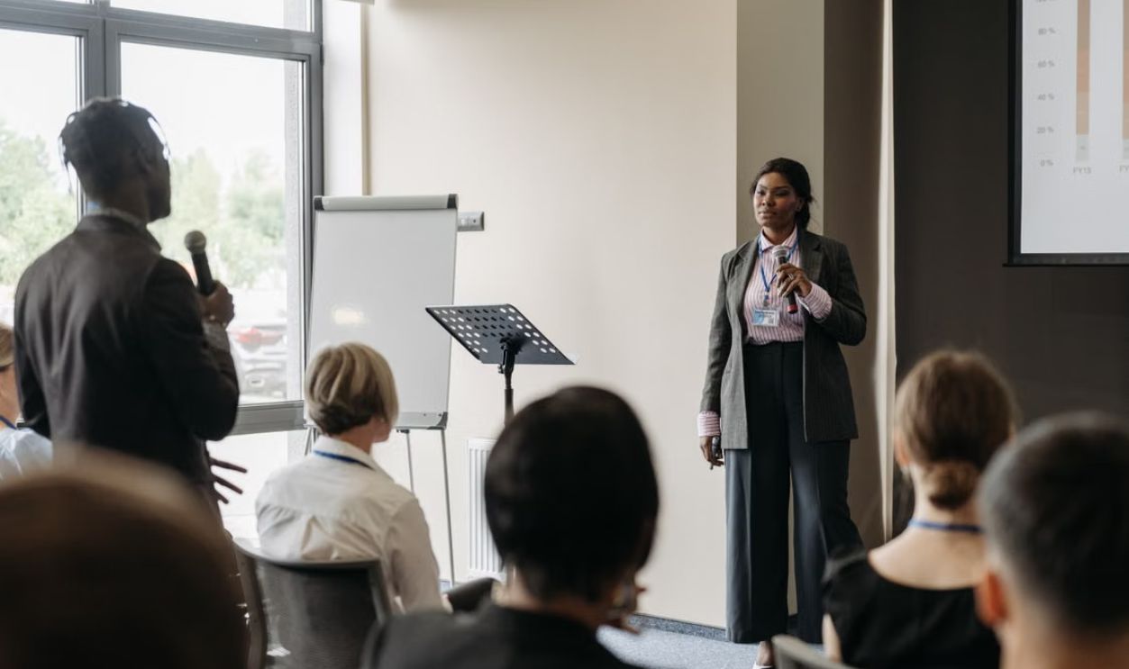 Professional business conference presentation with diverse participants engaging in communication.