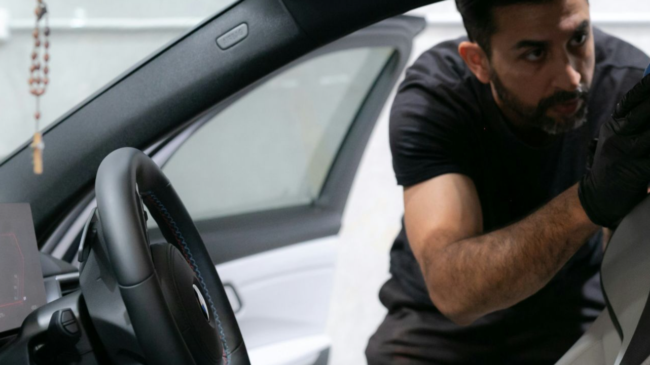 A man cleans a car seat inside the vehicle.