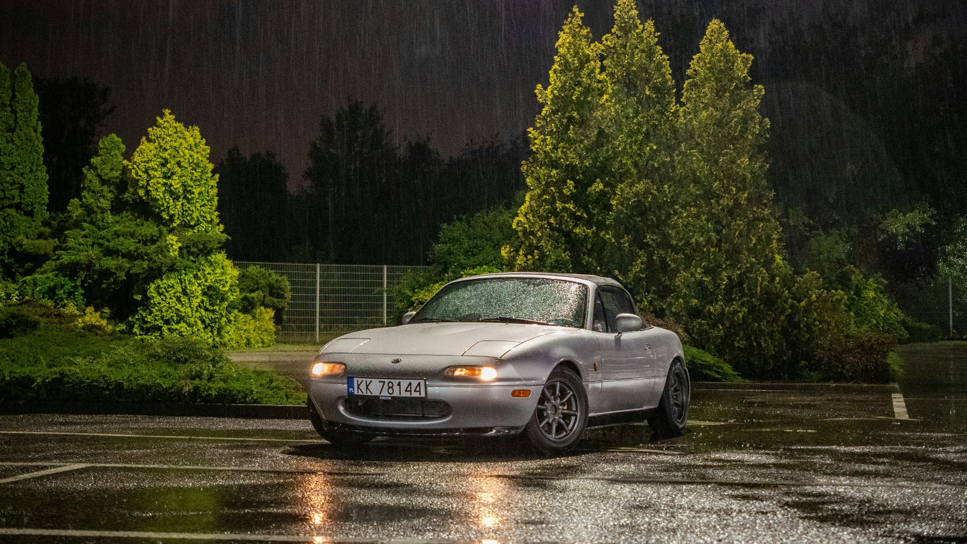 A car parked in a parking lot in the rain