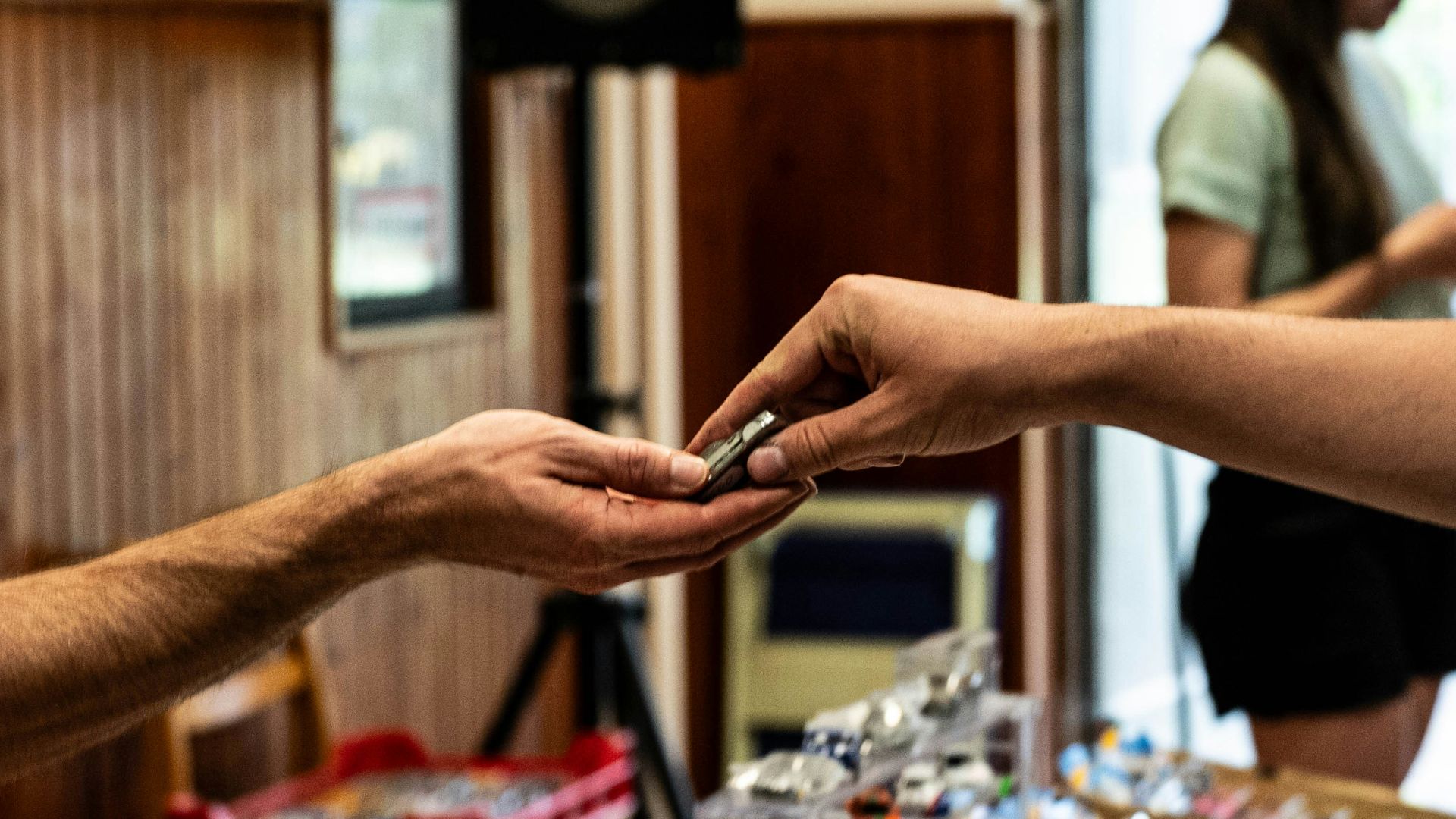 Hands exchanging a small metallic item.