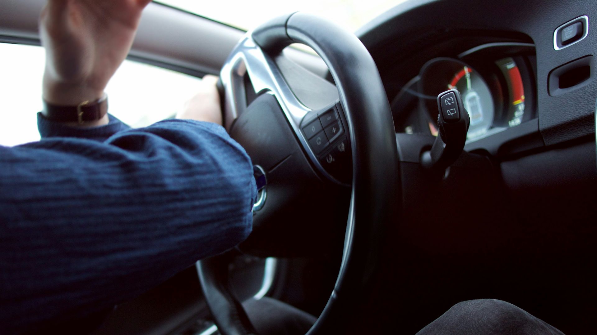 man holding black steering wheel