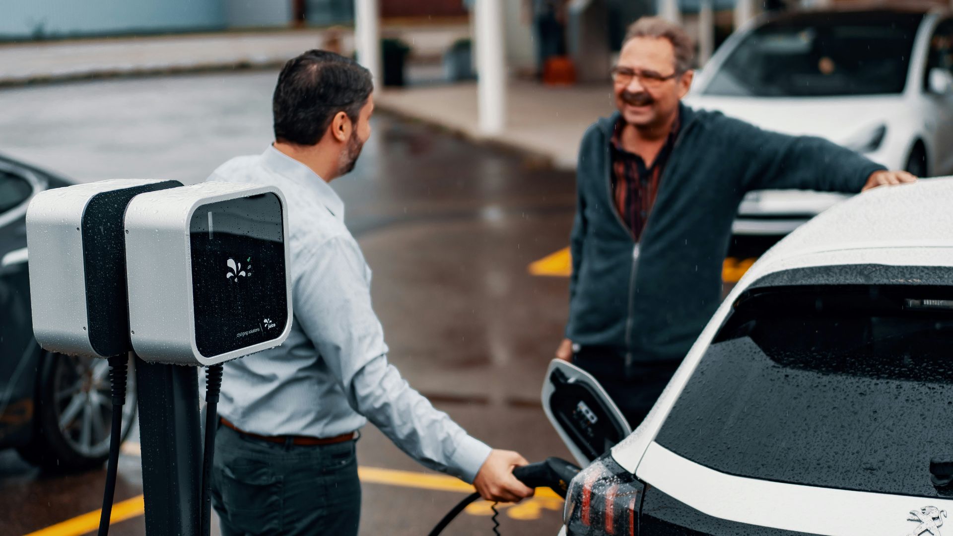 a couple of men standing next to a white car
