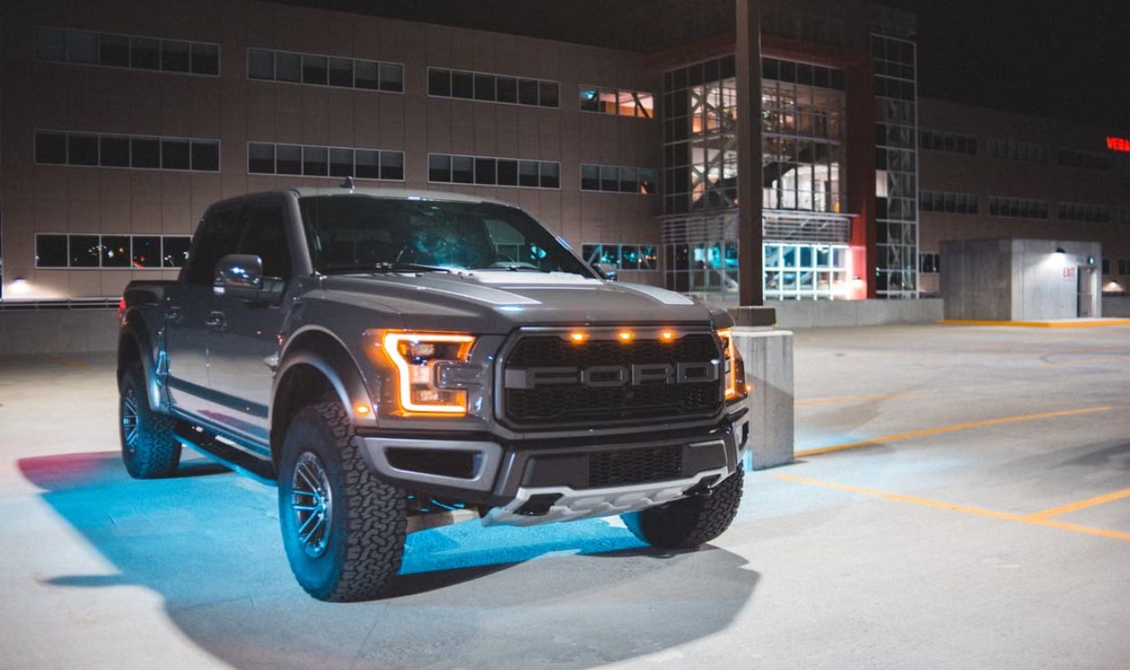 A sleek gray pickup truck parked in an urban area at night, showcasing modern design and headlights.
