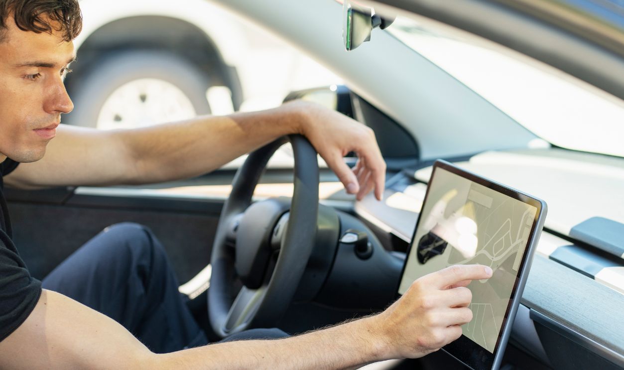 Man sets gps in modern electric car for road trip, showcasing seamless integration of digital features for connected driving