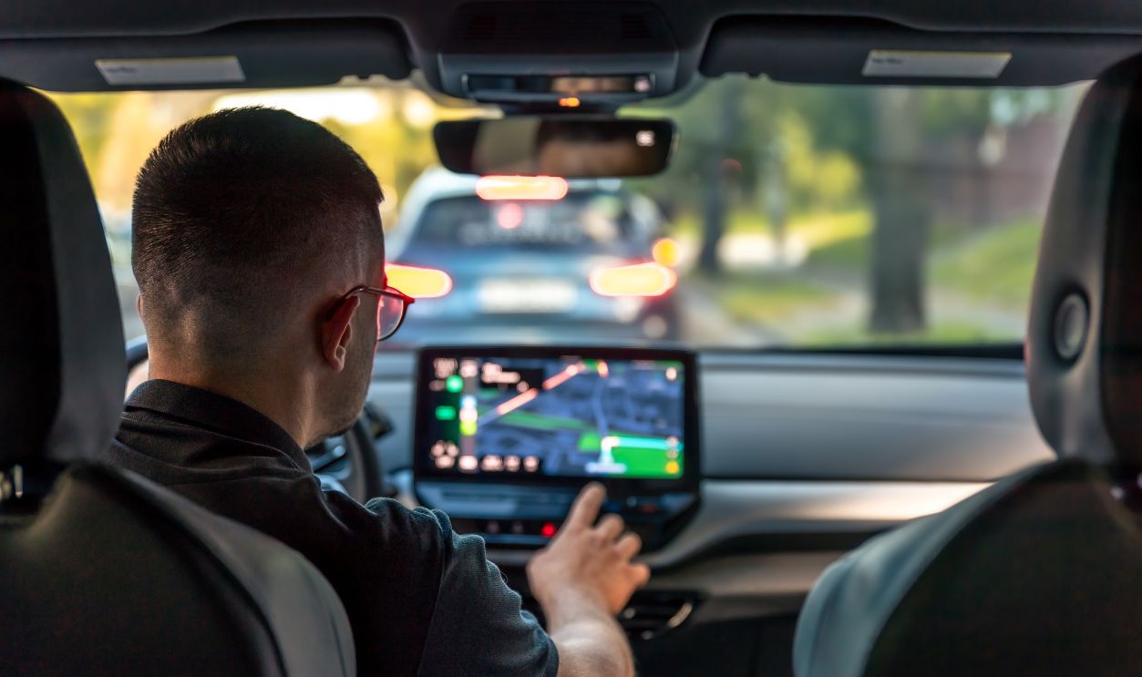 Man touching screen of a GPS navigation system in his car.