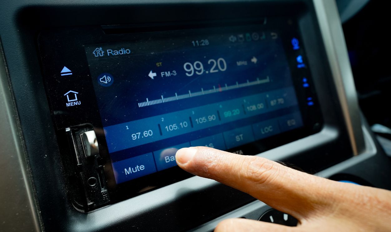 Hand touching the screen of the radio or music player in the car