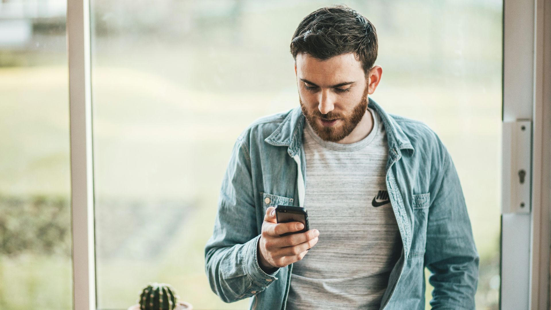 man holding a smartphone near the window