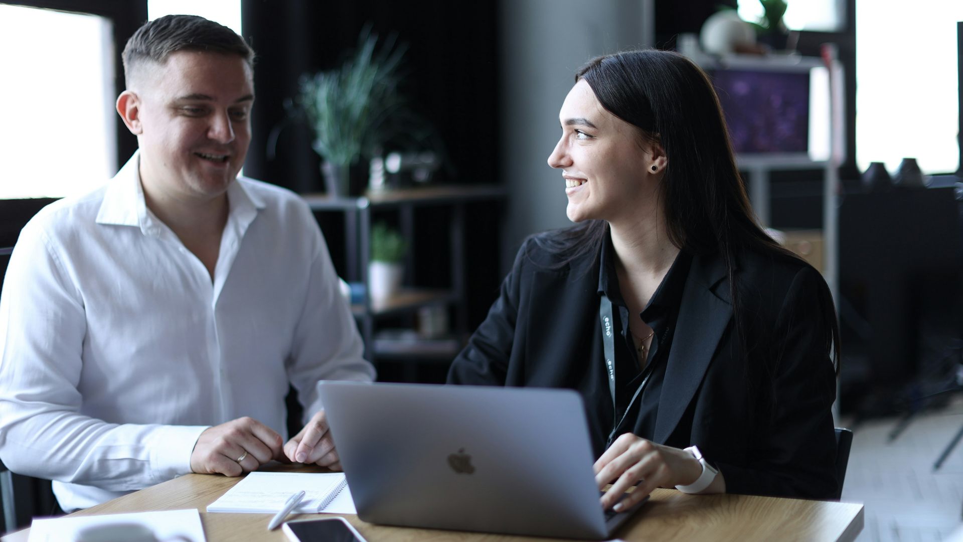 A man and a woman sitting at a table with a laptop