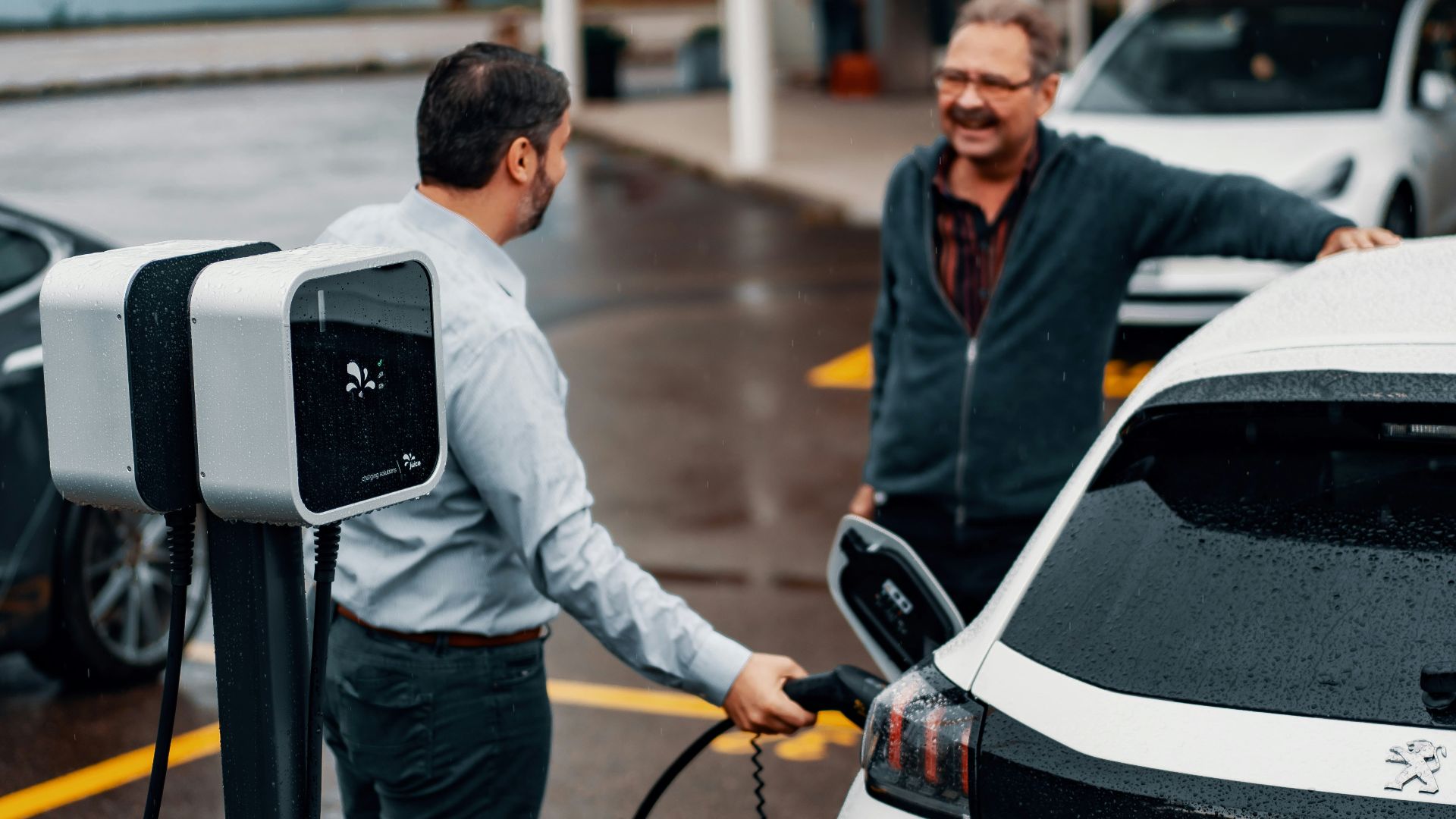 a couple of men standing next to a white car