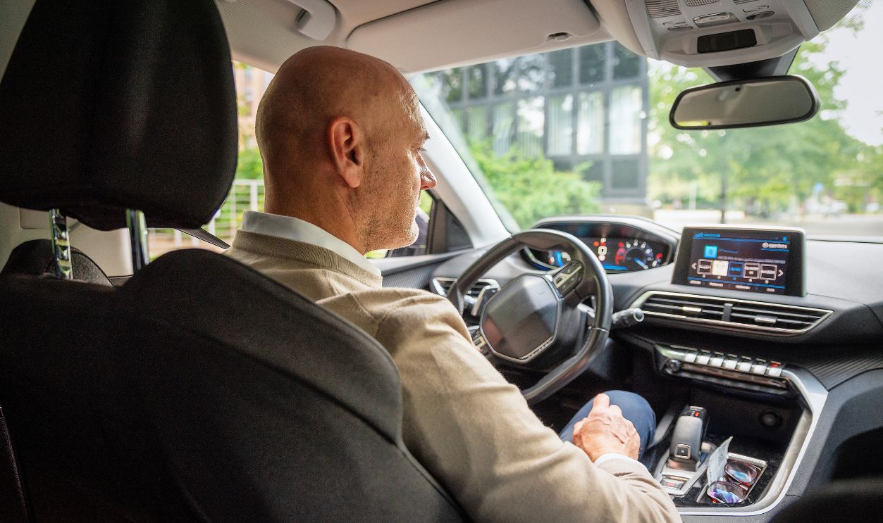 A middle-aged man is sitting in his car and driving. Confident male wearing casual clothes.