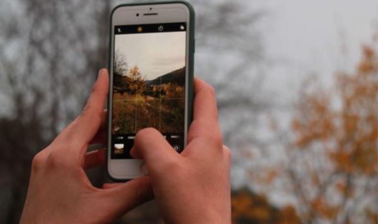 person-in-green-jacket-capturing-the-view-with-smartphone