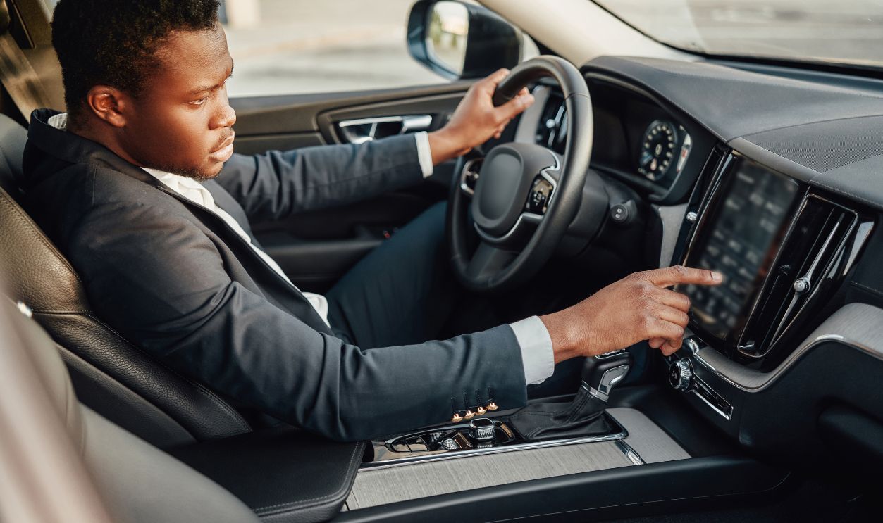 Black businessman inside car using car panel
