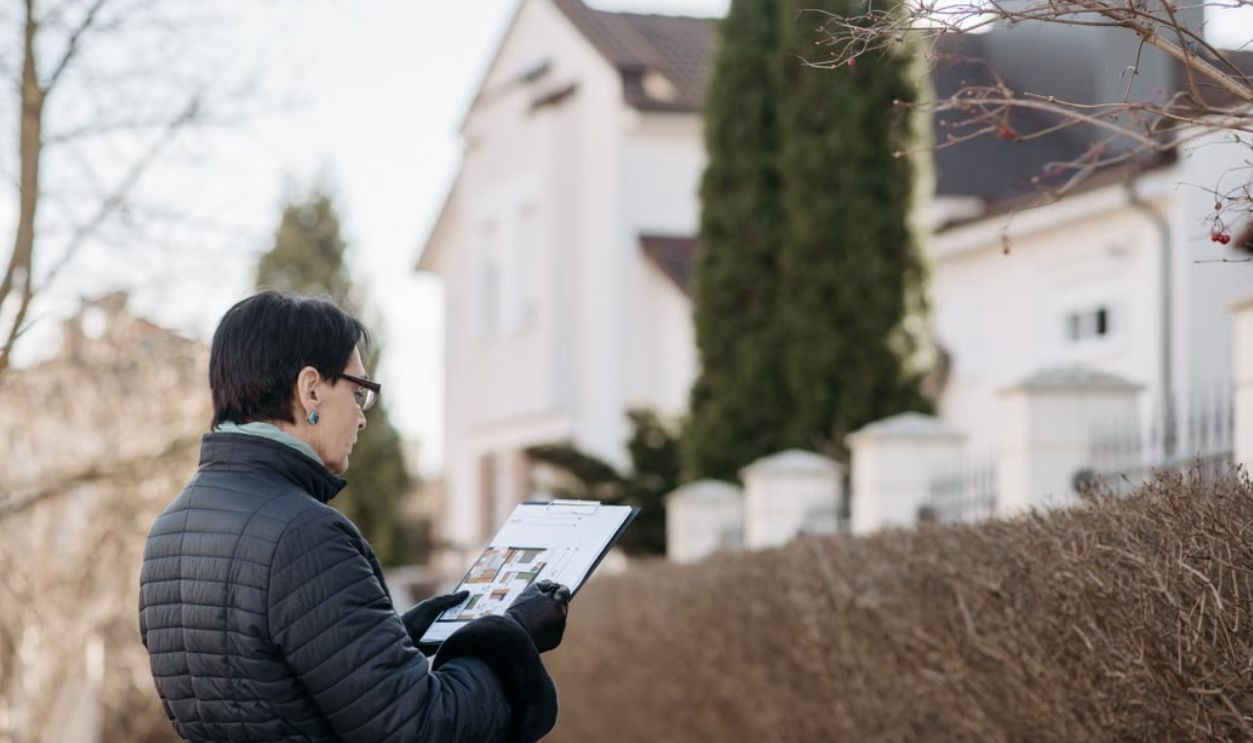 a-woman-standing-on-the-street-while-holding-a-house-plan