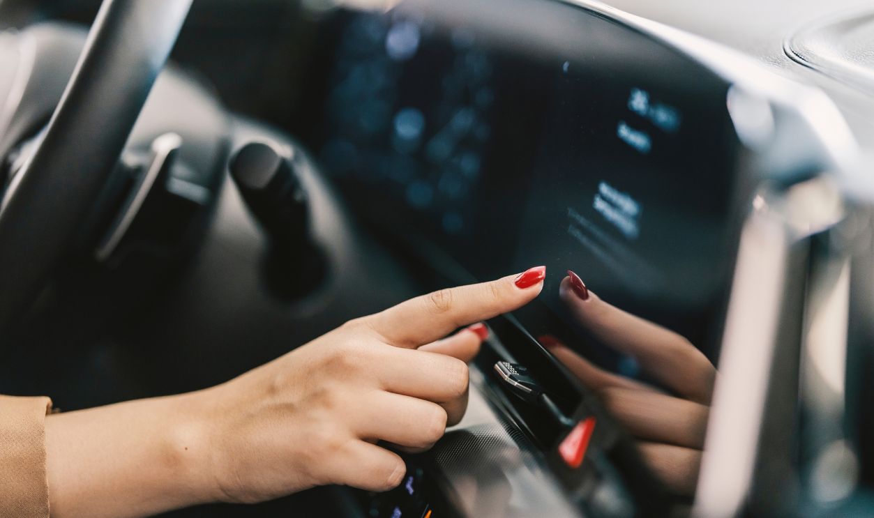 Hand pressing touchscreen in car.