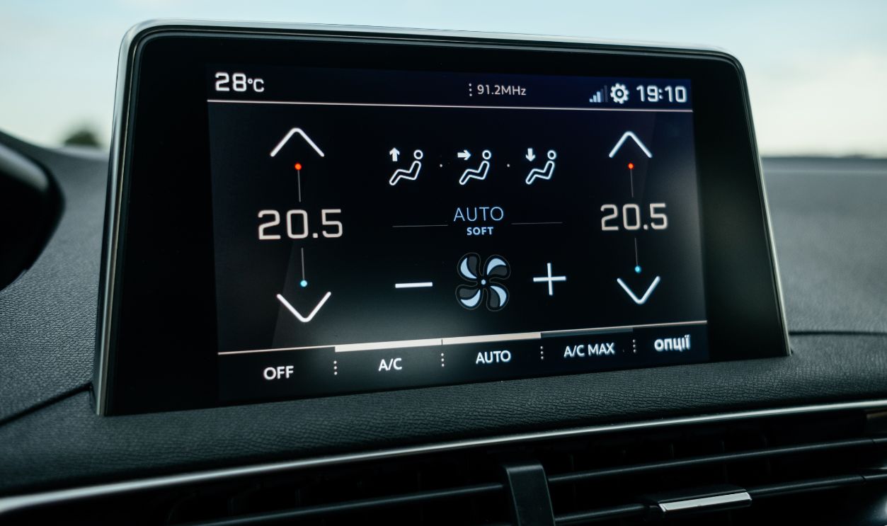 Interior details. Modern black car interior, leather steering wheel, climate control, large navigation system screen.