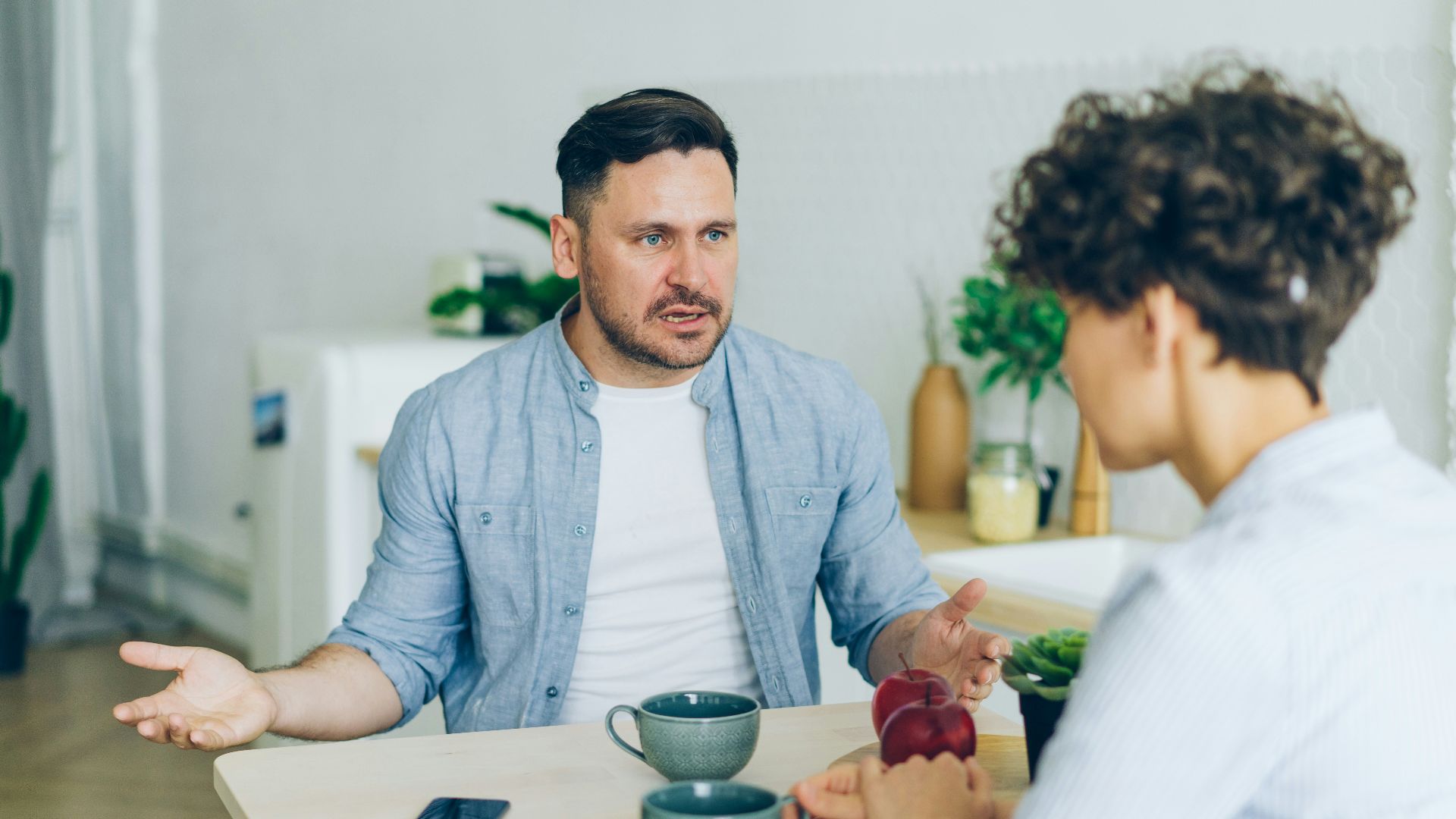 a man sitting at a table talking to a woman