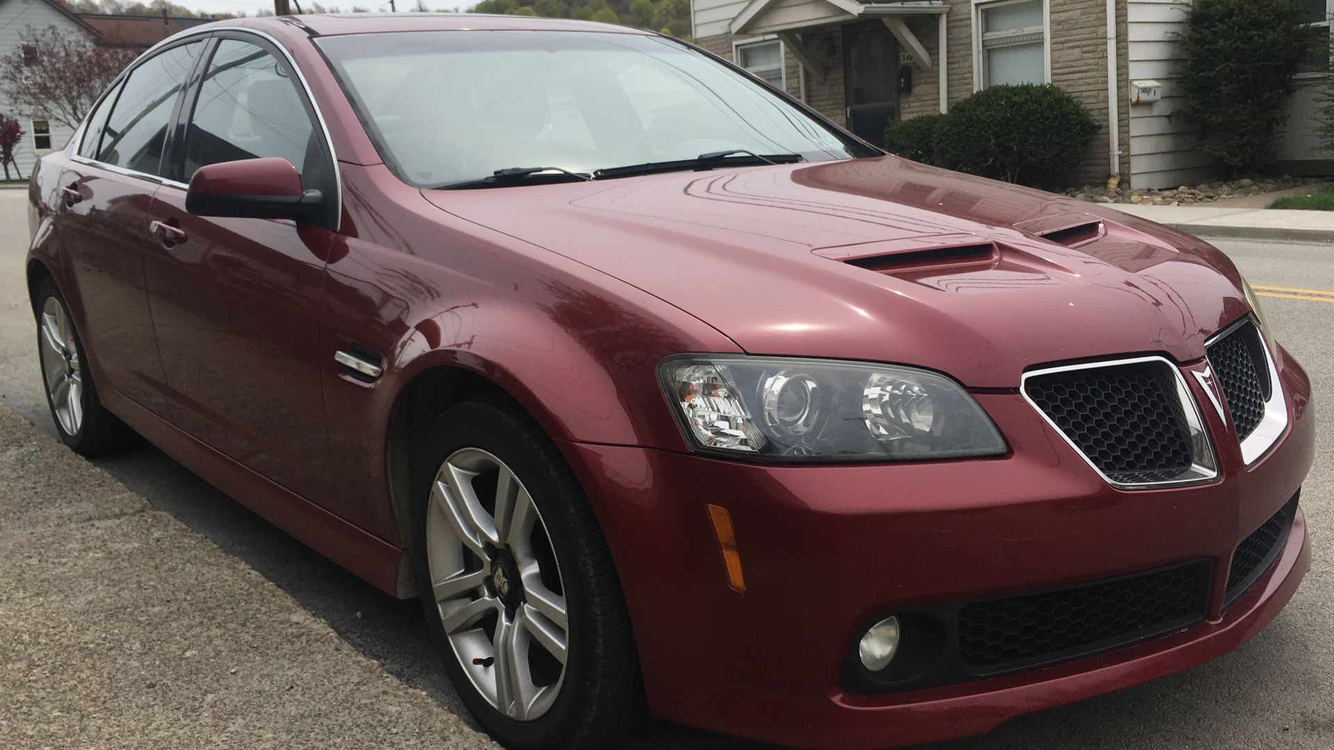 A 2009 Pontiac G8 in Sport Red Metallic. This G8 for some reason has an aftermarket Holden logo on the rear. This G8 is a base model, equipped with a 3.6L V6, and made in Elizabeth, South Australia.